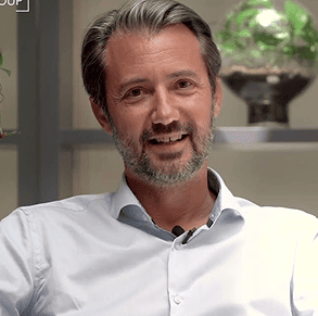 Un monsieur avec des barbes avec une chemise blanche.